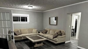 A living room with a sectional sofa, a coffee table, and a TV. There is a door leading to another room and a window with blinds. - Shaker Ohio contemporary home!

 (Cleveland)
