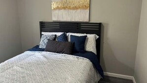 A bedroom with a bed, a headboard, and a wall-mounted abstract painting. - Shaker Ohio contemporary home!

 (Cleveland)