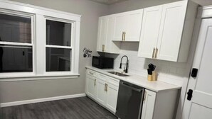 A kitchen with white cabinets, a black microwave, and a sink. - Shaker Ohio contemporary home!

 (Cleveland)