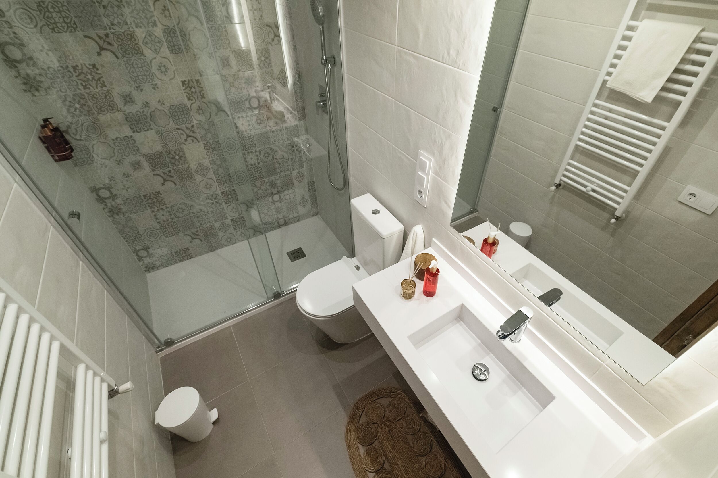 A modern bathroom with a glass shower enclosure, a white toilet, and a white sink with a mirror.