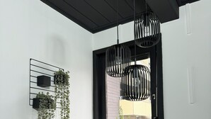 A staircase with a black railing leading to a landing. There are hanging plants on a wall-mounted shelf and a window with a view of the outside.