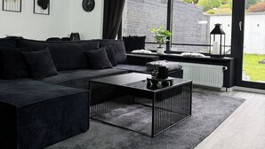 A modern living room with a sectional sofa, a coffee table, and a large window with a view of a garden.
