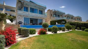 A modern multi-story building with a swimming pool, well-maintained garden, and outdoor seating area.