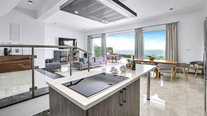 Una cocina moderna con una isla central, un comedor con vistas y una sala de estar con chimenea.
