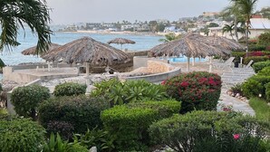 Un resort con area piscina, palme e vista sulla spiaggia.