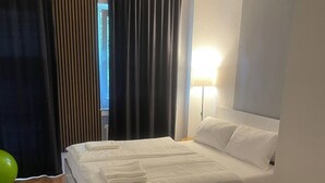 A neatly made bed with white linens, a green exercise ball, and a wooden floor. - Quiet apartment 4 min from the cathedral with office and balcony (Köln)