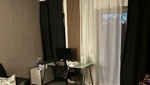 A modern living room with a sofa, a desk, and a computer. There is a window with curtains and a view of the outside. - Quiet apartment 4 min from the cathedral with office and balcony (Köln)