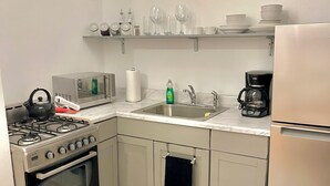 Une cuisine de taille réduite équipée d’une cuisinière, d’un four, d’un évier et d’un réfrigérateur.
