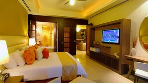 Quarto de hotel com cama, televisão, escrivaninha e espelho.