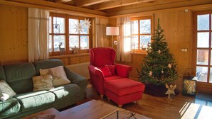 A cozy cabin interior with a green sofa, a red armchair, and a Christmas tree. - Chalet Glemm Alpin (Hinterglemm)