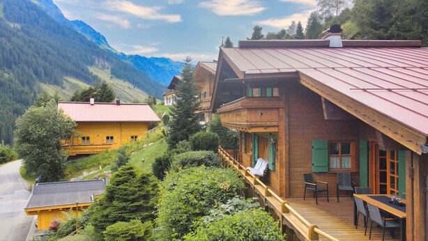 A wooden chalet with a balcony, surrounded by lush greenery and mountains. - Chalet Glemm Alpin (Hinterglemm)