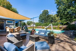 A backyard with a pool, outdoor furniture, and a slide.