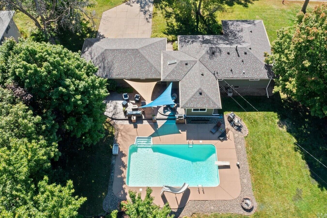 Propiedad residencial con una amplia piscina, un patio cubierto y una casa con techo inclinado.