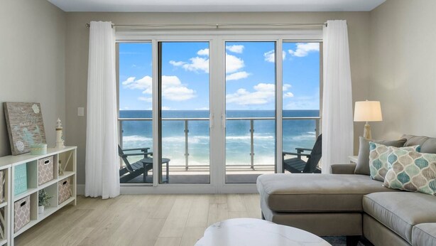 Ein Zimmer mit einer großen Schiebeglastür, die auf einen Balkon mit Meerblick führt.