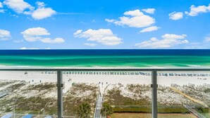 Blick auf einen Strand mit blauem Himmel, feinem Sand und ruhigem Meer.