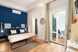 Ein Schlafzimmer mit einem Bett, einem Nachttisch, einem Spiegel und einer Glastür, die zu einem Außenbereich führt.
