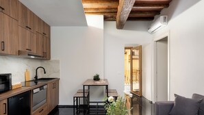 Una cucina compatta con mobili in legno, una lavastoviglie nera e un piccolo tavolo da pranzo con una pianta.