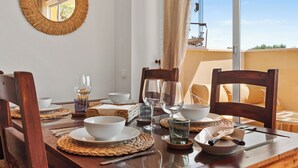 A dining table set with white bowls, wine glasses, and cutlery, surrounded by wooden chairs. - Casa Bonita de La Cala (Mijas)
