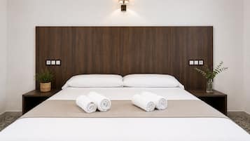 Habitación de hotel con una cama grande, dos mesitas de noche, una lámpara de pared y una planta en maceta.