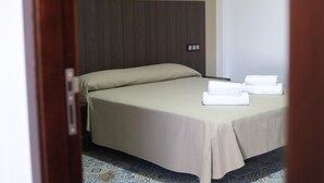 Een hotelkamer met een bed, hoofdeinde en een klein tafeltje met handdoeken.