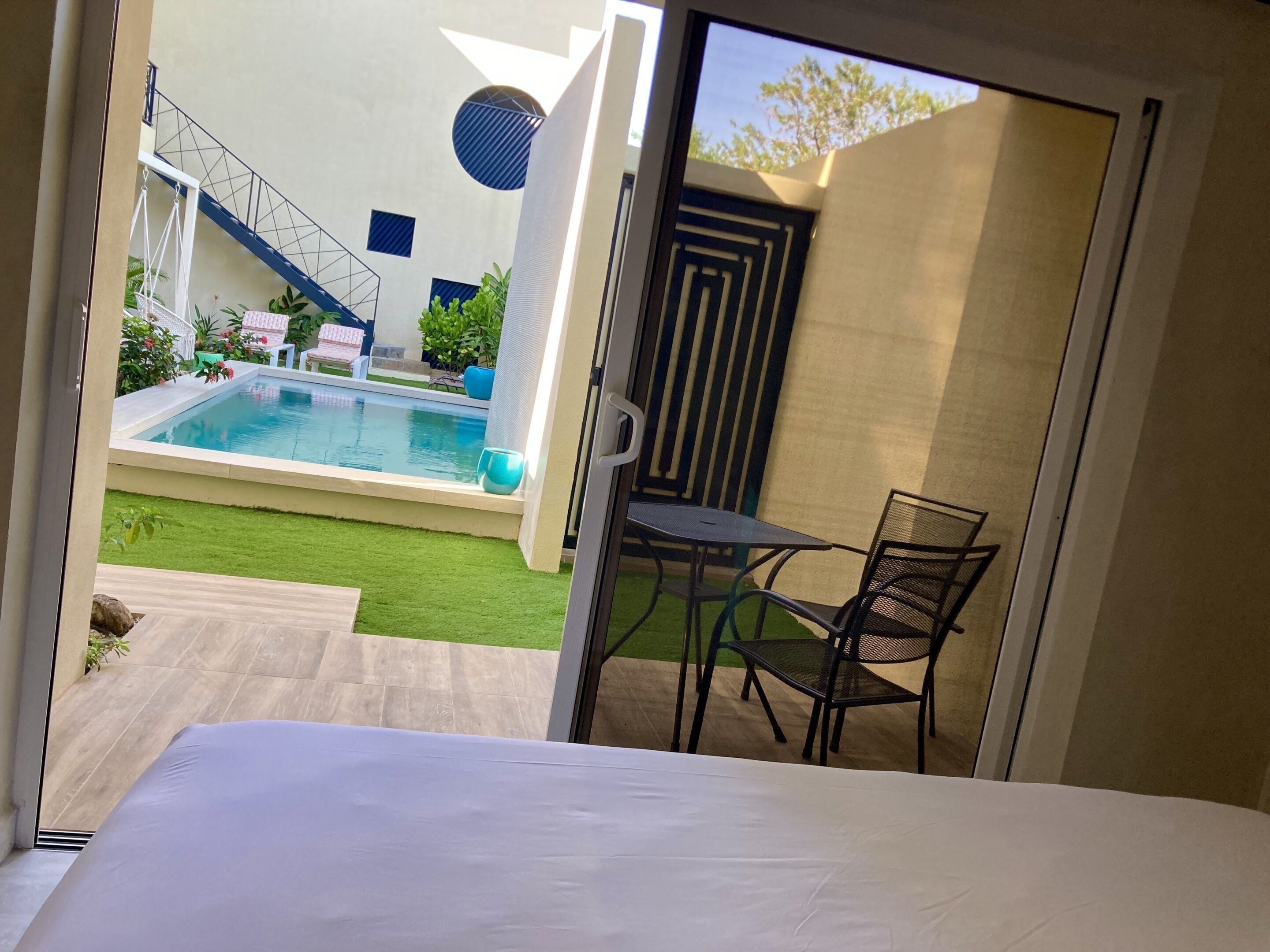 A bedroom with a view of a swimming pool, a staircase, and outdoor seating.