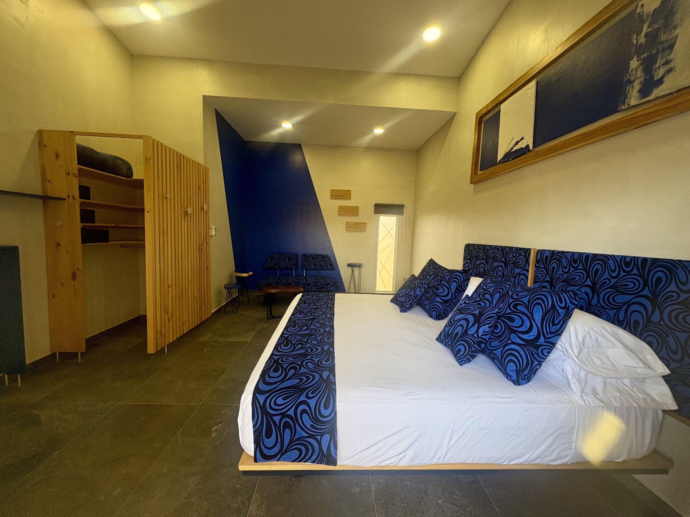 Quarto com uma cama grande, um guarda-roupa de madeira, uma escrivaninha e uma cadeira.