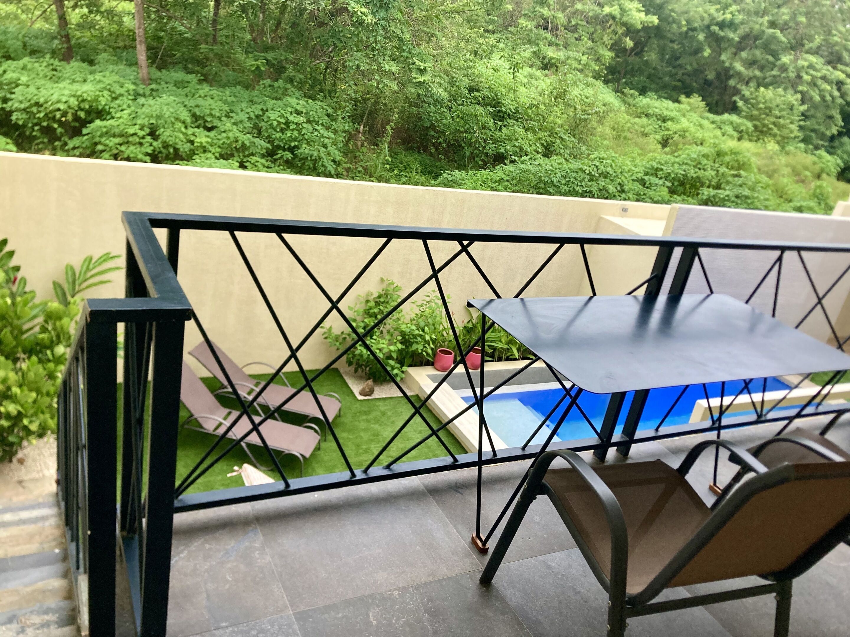 Un balcon donnant sur une piscine et une végétation luxuriante.