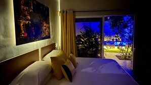 Camera d'albergo con un letto grande, un quadro appeso al muro e vista su un giardino illuminato.
