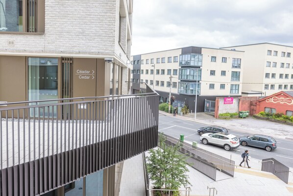 A modern building with a glass facade, a visible entrance, and a street with cars and pedestrians. - Crow's Nest (Cork)