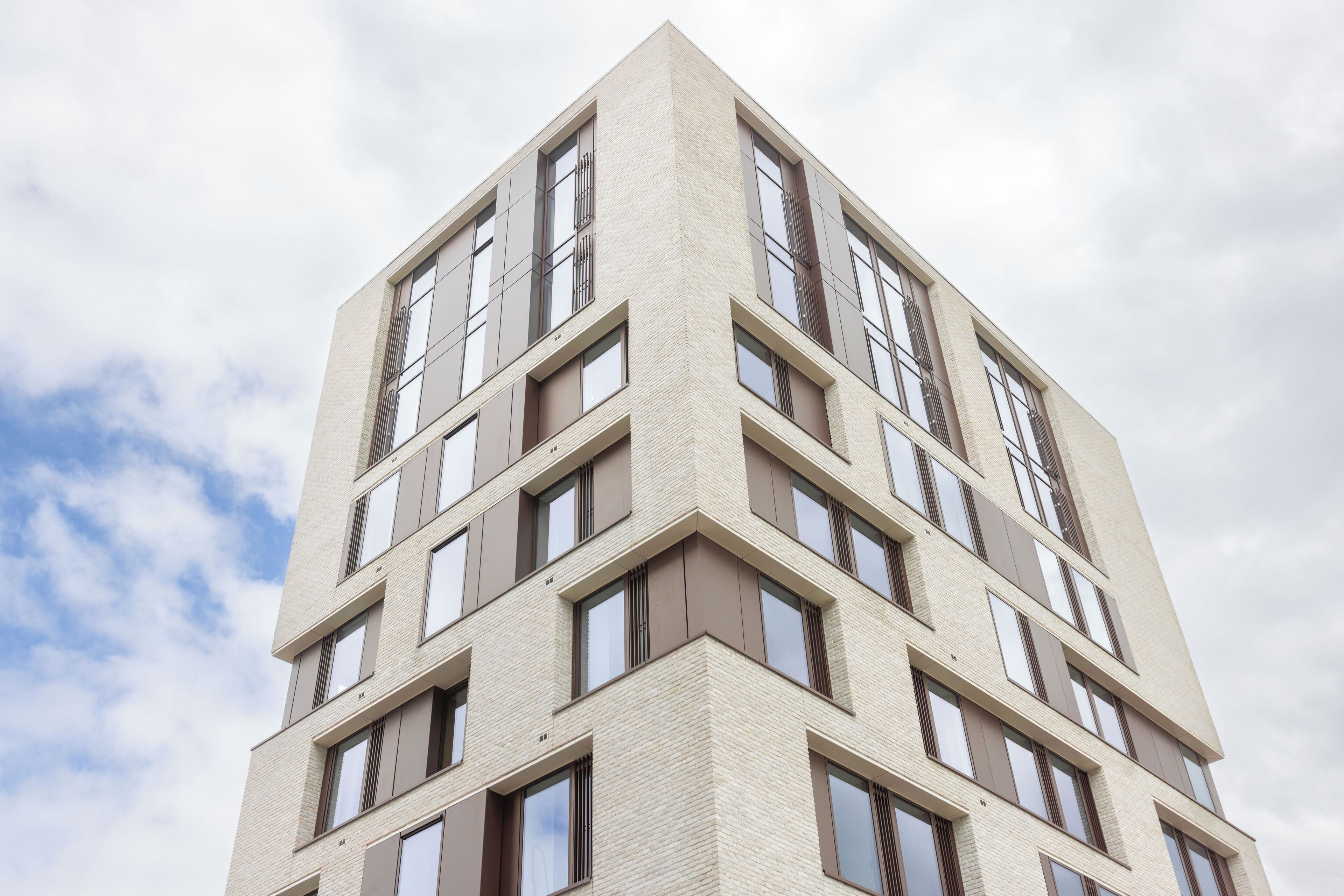 Ein mehrstöckiges Gebäude mit modernem architektonischen Design, das durch eine Reihe rechteckiger Fenster und eine neutrale Farbgestaltung gekennzeichnet ist.