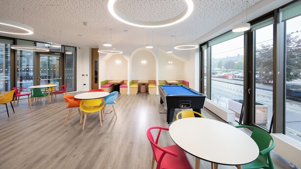A modern indoor space with a pool table, colorful chairs, and large windows offering a view of the street. - Crow's Nest (Cork)