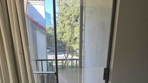 A hotel room with a bed, a sliding glass door to a balcony, and curtains. - Furnished and Spacious 2-Bedroom Apartment in Downtown Dallas Medical District (Dallas)