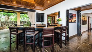 A kitchen with a wooden ceiling, a stone wall, and a view of greenery outside. - Beachfront Villa in  Playa Langosta, Tamarindo! (Playa Langosta)