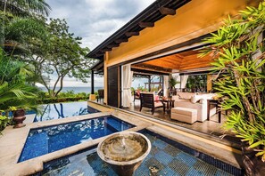 Zona de piscina con jacuzzi, mobiliario exterior y vista al mar.