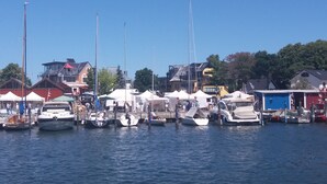 A marina with boats docked, buildings in the background, and a clear sky.