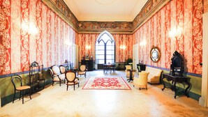 A room with ornate wallpaper, a large window, and a red carpet. - Palazzo Insula (Gallipoli)