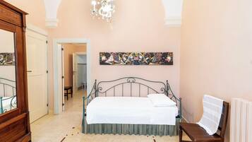 A bedroom with a bed, a chair, a dresser, and a chandelier.