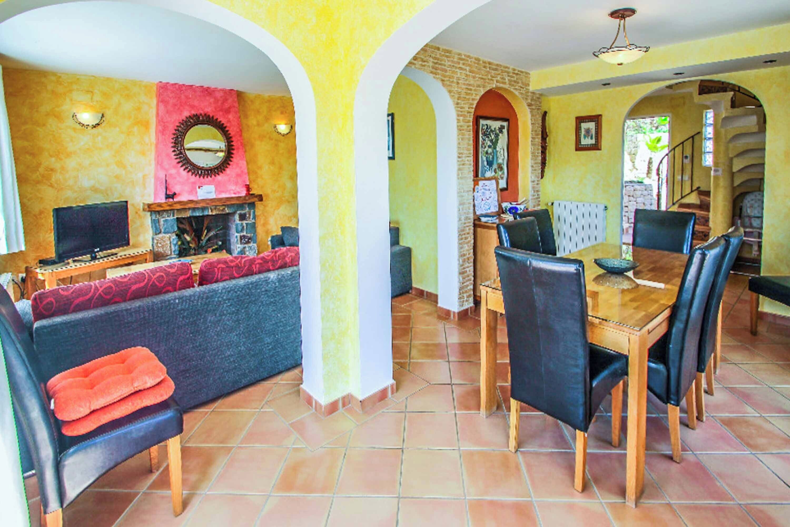 A spacious living area with a fireplace, a dining table with chairs, and a sofa with cushions.
