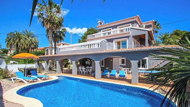Un bâtiment à deux étages doté d’une piscine, d’un espace extérieur aménagé et de palmiers.