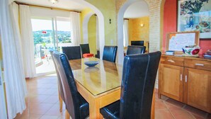 Un coin repas avec une table à plateau en verre, des chaises noires et des meubles de rangement en bois.