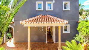 Un bâtiment à la façade grise, doté d’un toit en tuiles et d’un espace d’entrée abrité.