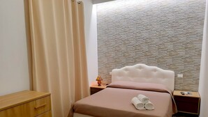 Un dormitorio con cama, cómoda de madera y pared con textura de piedra.