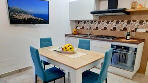 Una cocina moderna con una mesa de comedor, sillas y un televisor que muestra una vista panorámica.