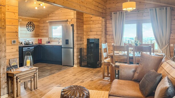 A wooden cabin interior with a kitchen, dining area, and living room. - 3 bedroom accommodation in Falkirk (Falkirk)