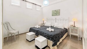 Une chambre avec deux lits, une chaise, une table de chevet et une lampe.