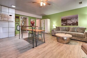 A living room with a green wall, a sofa, a coffee table, and a dining area with a table and chairs. - Designer Condo in Hip Zen Yard! Midtown Phoenix! (Phoenix)