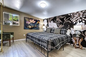 A bedroom with a bed, a chair, a nightstand, and a wall with floral wallpaper. - Designer Condo in Hip Zen Yard! Midtown Phoenix! (Phoenix)