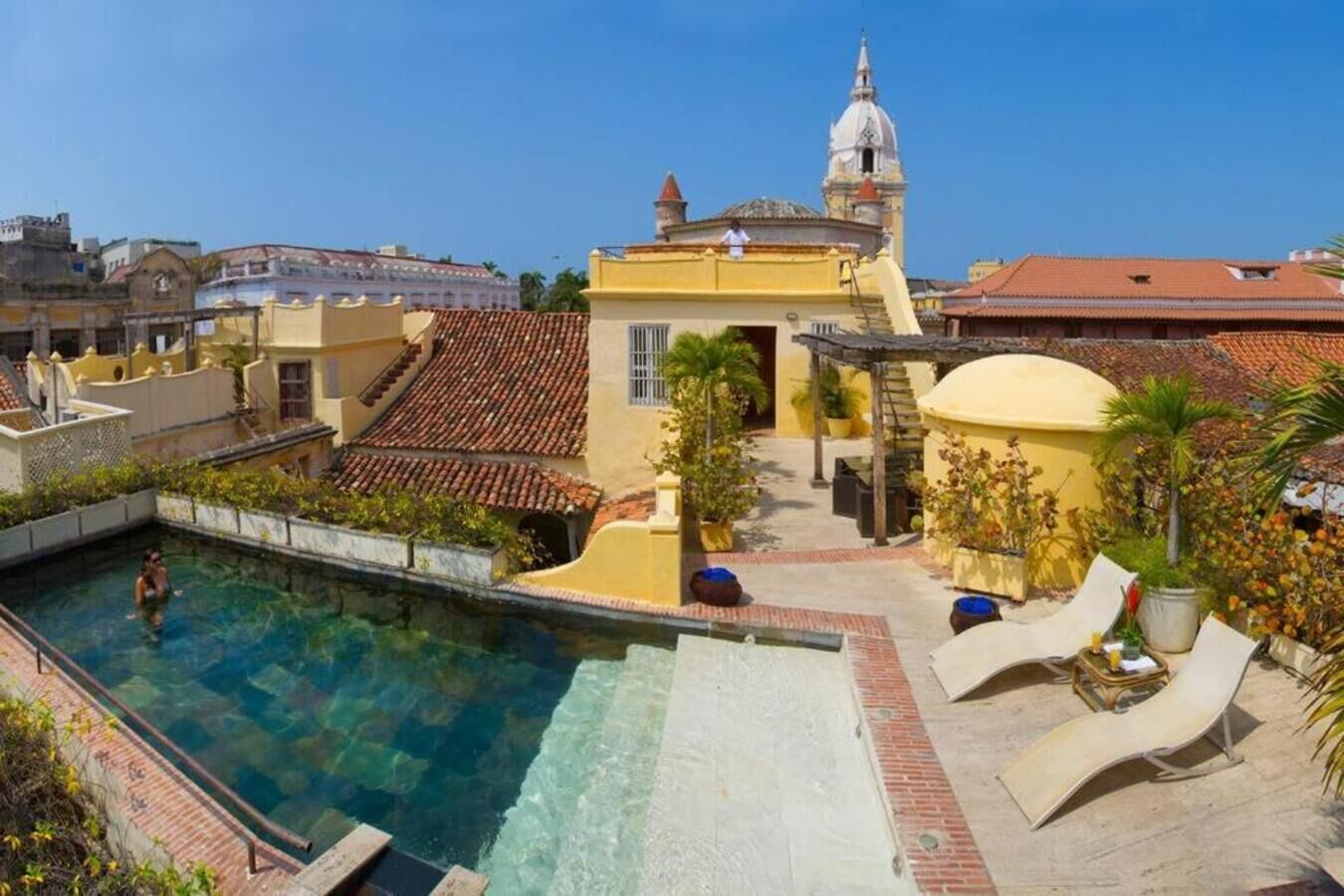 A pool area with a clear water pool, a small waterfall feature, and a lounge area with sun loungers.