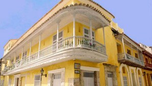 A yellow building with a balcony and a white railing. - Casa Pombo 102 (Cartagena)