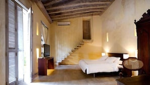A bedroom with a bed, a television on a stand, a staircase, and a wooden ceiling. - Casa Pombo 102 (Cartagena)